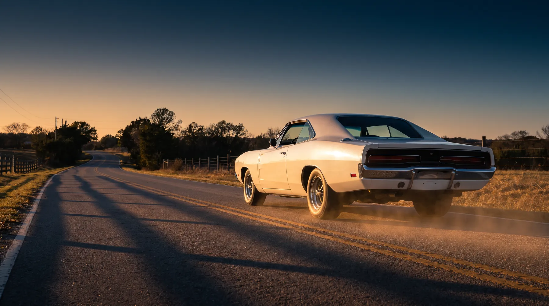 Weißer amerikanischer Oldtimer fährt bei Sonnenuntergang über eine Landstraße
